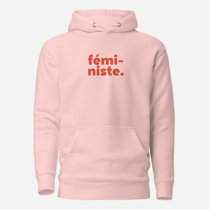 Light Pink hoodie, front view, with red stacked 'fémi-niste.' lettering.